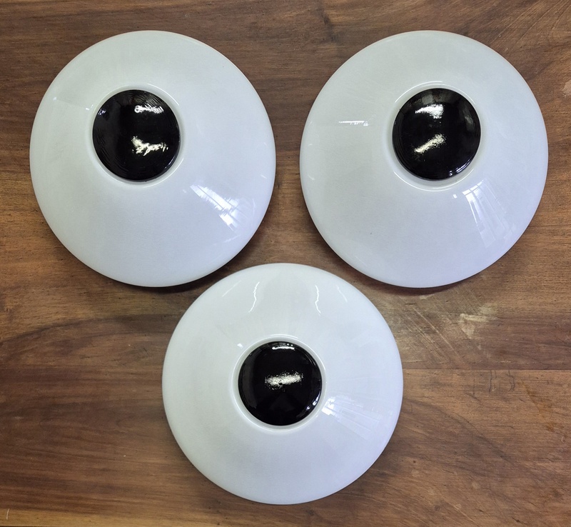 Applique bianche con bottone nero centrale.